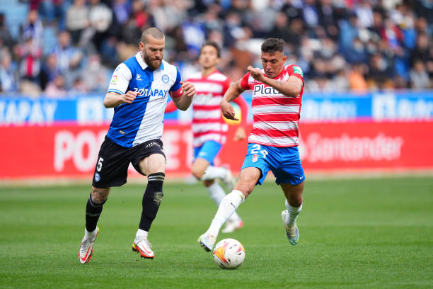 Myrto Uzuni of Granada CF battles for possession with Victor Laguardia of Deportivo Alaves during the LaLiga Santander match between Deportivo Alaves...