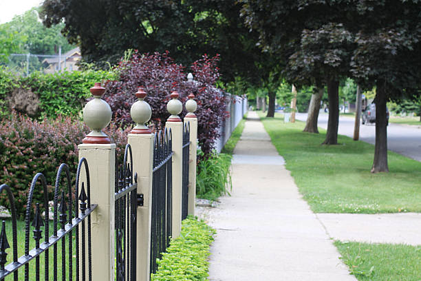 neighborhood sidewalk with fence posts picture