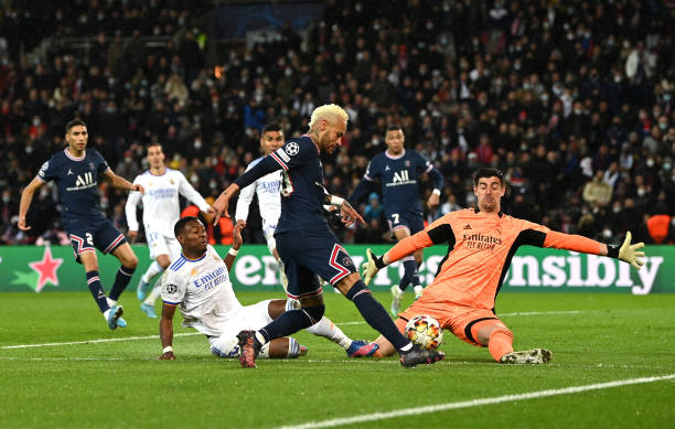 Neymar of Paris Saint-Germain shoots past Thibaut Courtois of Real Madrid during the UEFA Champions League Round Of Sixteen First Leg match between...