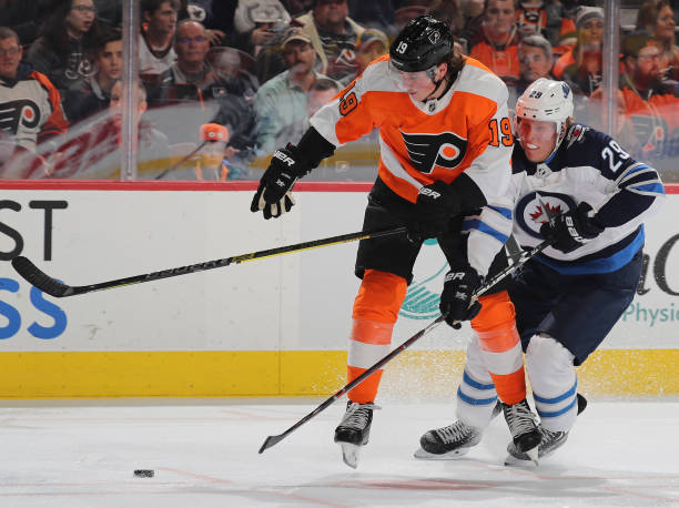 Nolan Patrick of the Philadelphia Flyers and Patrik Laine of the Winnipeg Jets fight for the puck in the second period at Wells Fargo Center on...