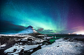 Northern lights in Mount Kirkjufell Iceland with a man passing by