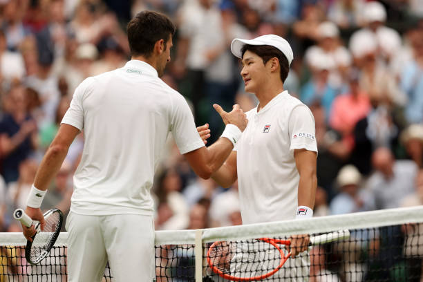 Novak Djokovic of Serbia interacts with Soonwoo Kwon of South Korea after winning their Men's Singles First Round match during Day One of The...