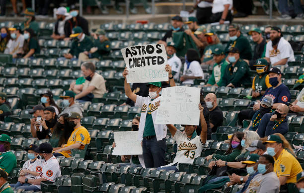 Oakland Athletics fans hold up signs about the Houston Astros cheating during their Opening Day game at RingCentral Coliseum on April 01, 2021 in...