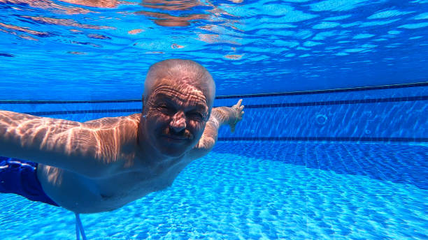 old man swimming underwater in swimming pool picture