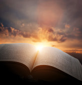 Open old book, light from sunset sky, heaven. Education, religion concept