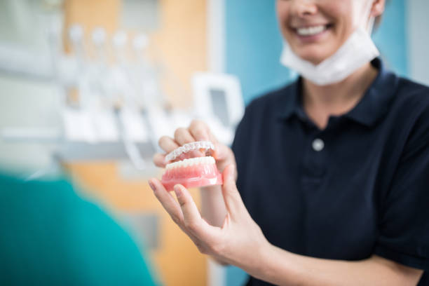 orthodontist explaining an implant to a patient in clinic - prótese dentaria - fotografias e filmes do acervo