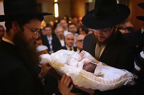 Orthodox Jews pass baby infant Mendl Teichtal to one another before his circumcision at the Chabad Lubawitsch Orthodox Jewish synagogue on March 3,...