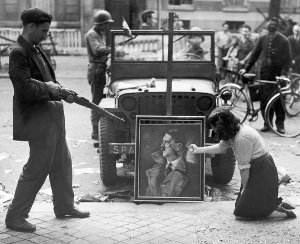 Parisians express their feelings towards a defaced portrait of Nazi leader Adolf Hitler the day after the surrender of the German garrison in the...