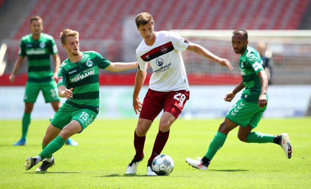 Patrick Erras of 1 FC Nuernberg is challenged by Sebastian Ernst and Julian Green of SpVgg Greuther Fuerth during the Second Bundesliga match between...