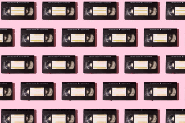 Pattern of black VHS video tapes with hard shadow on pink background. Video, movies, retro, vintage, obsolete system, magnetic and cinema concept.