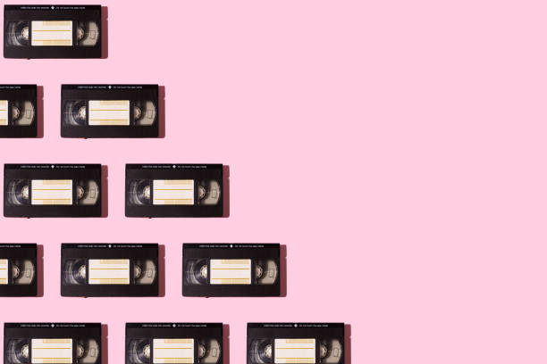 Pattern of black VHS video tapes with hard shadow, on the left side, on pink background. Video, movies, retro, vintage, obsolete system, magnetic and cinema concept.