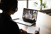 Pc screen view over woman shoulder during group videocall elearning