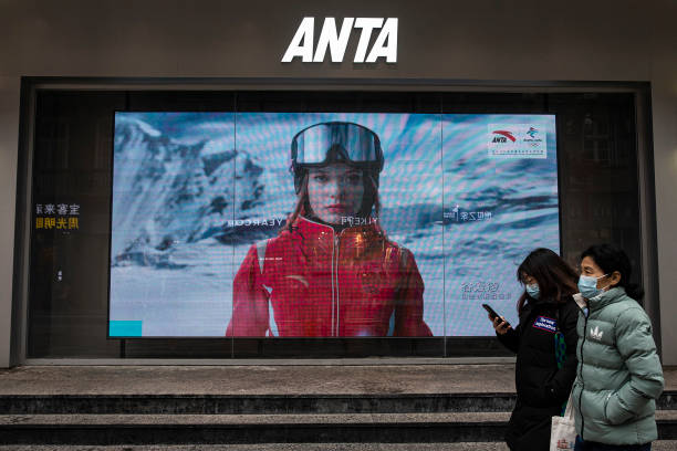 People walk in front of an advertising video of freestyle skiing gold medalist Eileen Gu who competes for China At Anta store on February 9, 2022 in...