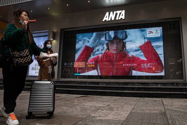 People walk in front of an advertising video of freestyle skiing gold medalist Eileen Gu who competes for China At Anta store on February 9, 2022 in...