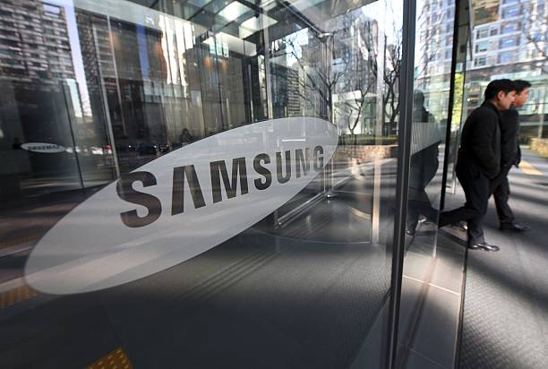 people walk past the samsung logo at the samsung group headquarters picture