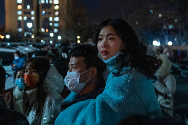 People watch the the opening ceremony of Beijing 2022 Winter Olympics from a parking lot outside of Beijing National Stadium on February 04, 2022 in...