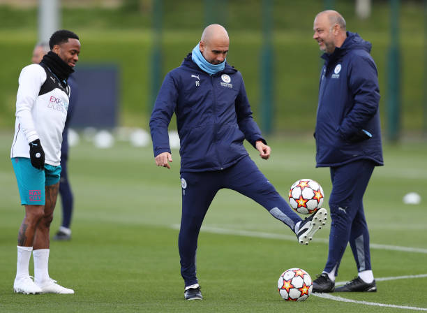 Pep Guardiola, Manager of Manchester City controls the ball as Raheem Sterling of Manchester City looks on during the Manchester City Training...