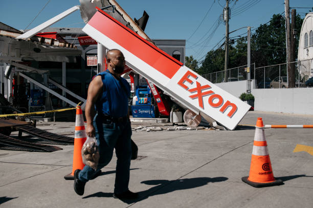 Person carrying a bag of potatoes walks past a gas station in the Whitestone neighborhood of Queens that was heavily damaged after a night of...