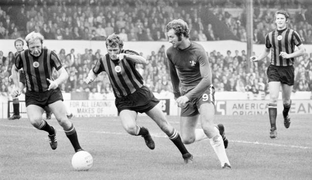 Peter Osgood of Chelsea races past Tony Book and David Connor of Manchester City during their Division One football match at Stamford Bridge in...