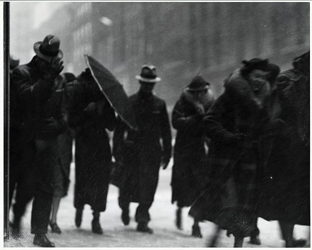 Photo shows pedestrians walking on a windy, rainy day. Ca. 1920s.