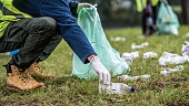 Picking up a plastic bottle during park clean-up