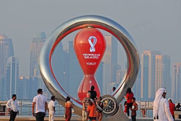 Picture taken on October 20 shows people walking past the Qatar 2022 FIFA World Cup countdown clock as it nears marking thirty days, in the Qatari...