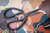 Pieces of colorful leather and scissors, workshop, manufacturing of fashion accessories. Top view.
