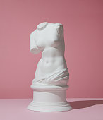 Plaster torso of Venus on pink background