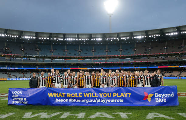 Players and Coaches pose for a photograph in front of the Beyond Blue banner during the 2022 AFL Round 12 match between the Hawthorn Hawks and the...