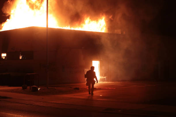 Police officer stands guard in front of a department of corrections building after it was set ablaze during a second night of rioting on August 24,...