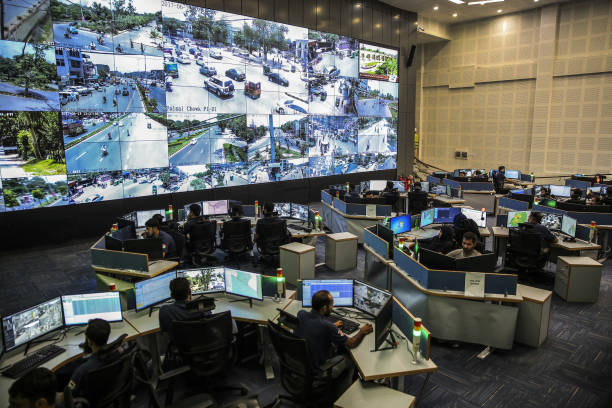 Police officers observe live video feeds from various locations around the city on monitors at the Punjab Police Integrated Command Control and...