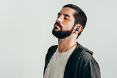 Portrait of a young bearded man wearing sports clothes and wireless earphones.