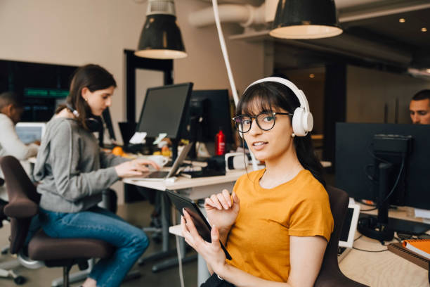 portrait of female it professional using digital tablet while coworkers working in creative office - professional software developer stock pictures, royalty-free photos & images