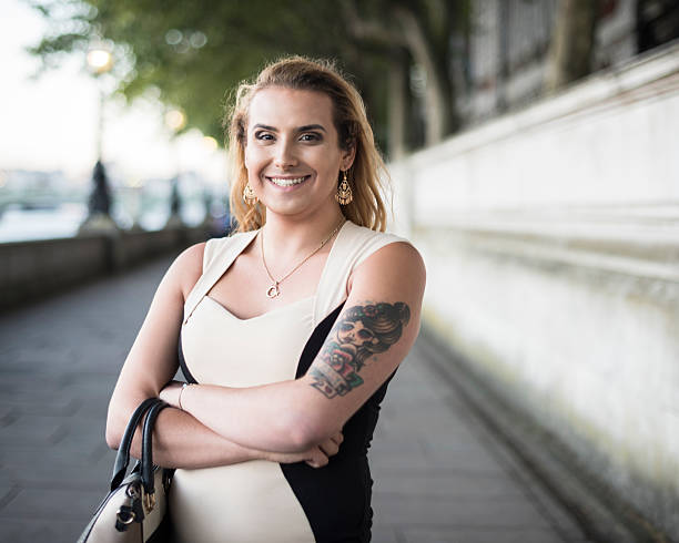 Portrait of happy transgender female with handbag and tattoo