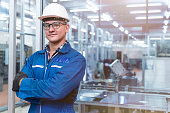 Portrait of manual man worker is standing with confident with blue working suite dress and safety helmet in front the glass wall of high technology clean industry factory.Concept of smart industry worker operating.