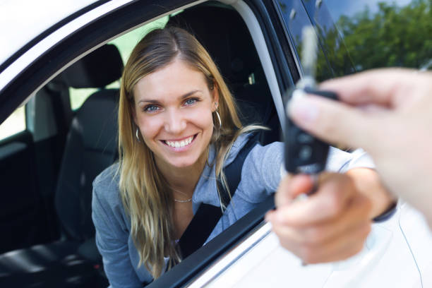 portrait of smiling young woman looking at camera while holding car picture