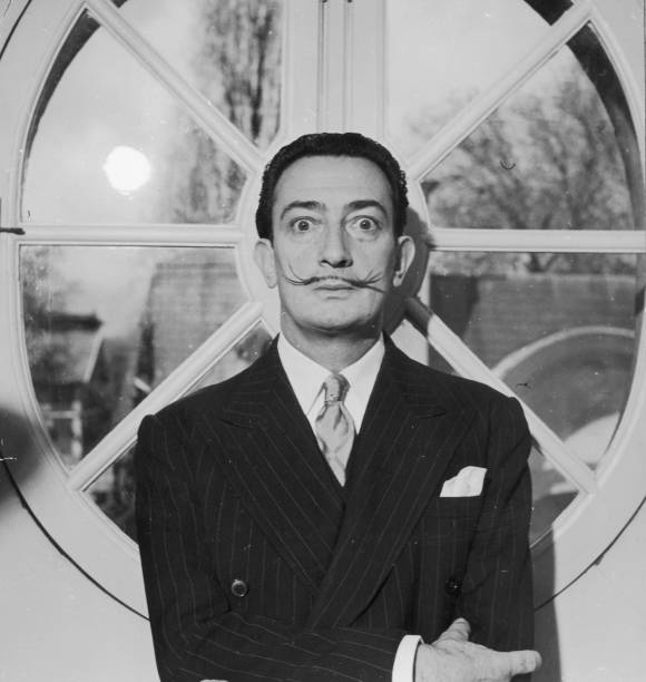 Portrait of Spanish surrealist artist Salvador Dali . He is wearing a pinstriped suit and his trademark mustache.