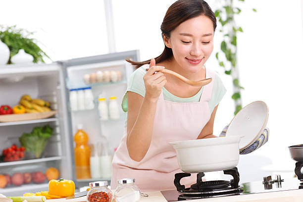 portrait of young woman cooking in kitchen - asian woman cook stock pictures, royalty-free photos & images