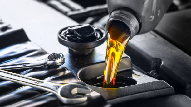 verser de l’huile moteur pour véhicules automobiles d’une bouteille grise dans le moteur - huile moteur photos et images de collection