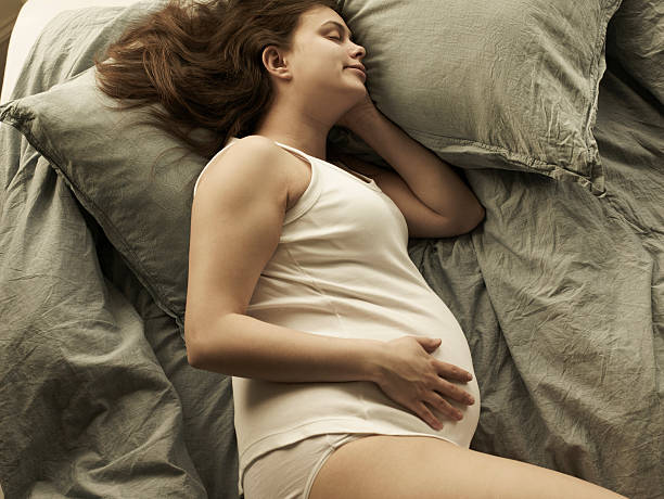 pregnant woman sleeping on bed, high angle view - pregnancy sleeping stock pictures, royalty-free photos & images
