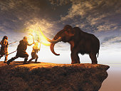 Prehistoric men hunting a young mammoth