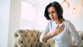 Pressure in the chest. Close-up photo of a stressed woman who is suffering from a chest pain and touching her heart area.