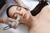 Professional female cosmetologist doing hydrafacial procedure in Cosmetology clinic.