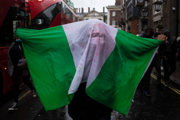 Protester covers themselves in a Nigeria flag outside the Nigerian High Commission during a protest calling for the end of police killings of the...