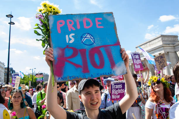 Protester holds a sign highlighting Pride's roots in protest at a London Trans+ Pride march from the Wellington Arch to Soho on 9th July 2022 in...