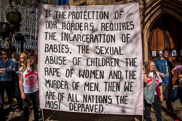 Protesters hold signs at a rally to demand all asylum seekers and refugees be brought to Australia following PNG government's decision to close the...