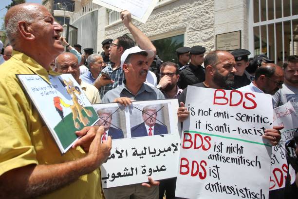Protesters stage a demonstration outside Germany's Representative Office in Ramallah in the Palestinian West Bank on May 22 following the Bundestag's...