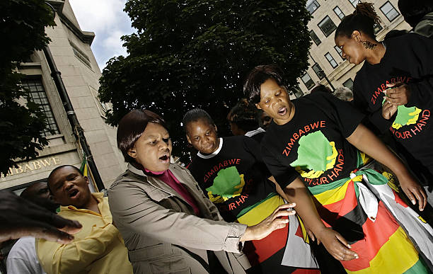 Protestors sing outside the Zimbabwe Embassy in London 13 October 2007 to mark the fifth anniversary of the weekly vigil to campaign against human...