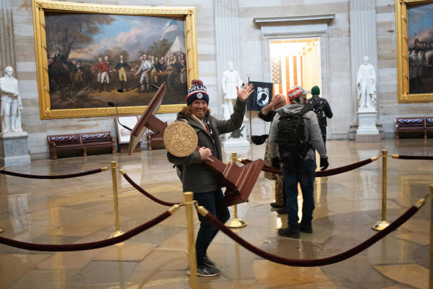 Pro-Trump protester carries the lectern of U.S. Speaker of the House Nancy Pelosi through the Roturnda of the U.S. Capitol Building after a pro-Trump...