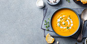 Pumpkin, carrot cream soup in a bowl. Grey background. Top view. Copy space.